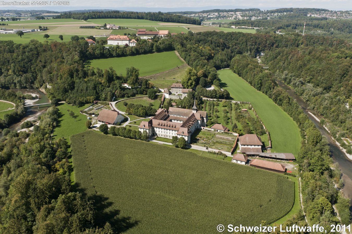 Zisterzienserabtei 'Abbaye de Hauterive' (Position: 2'575'526.80, 1'179'357.35) am Ufer der Sarine. 1138 vom Bischof von Lausanne als 'Abbatia sancte Marie de Altaripa' geweiht und 1848 aufgehoben. Danach landwirtschaftliche Schule, ab 1859 kantonales Lehrerseminar. Um 1939 besiedeln Mönche aus Wettingen-Mehrerau die Gebäude, und seit 1973 ist das Kloster wieder eine Zisterzienserabtei. - Im Hintergrund des Bildes links: Fribourg; rechts: Villars dur Glâne. Markantes Gebäude obere Bildmitte: ehemalige landwirtschaftliche Schule Grangeneuve.